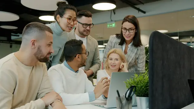 A corporate team and startup founders working together around a laptop